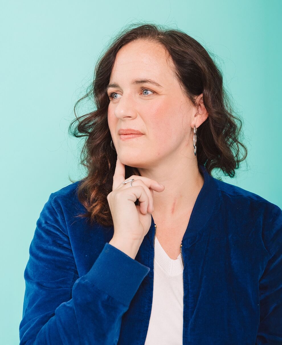 Katrin Siemens smiling and leaning with her hand against the wall of a building
